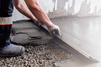 worker levels a floor cement for repair